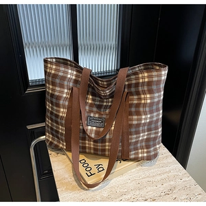 Gros plan d'un sac cabas en toile à carreaux marron vintage sur une surface en marbre