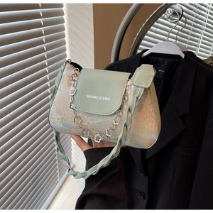 Detail of mint green baguette bag with gold landscape print and floral silver chain