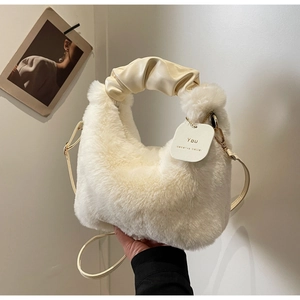 Detail of white plush faux fur bag with ruched leather handles and gold strap hardware