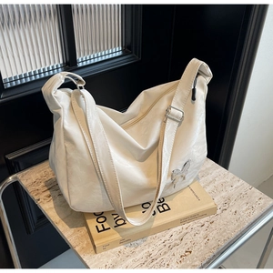 Détail du sac bandoulière en cuir blanc avec boucle papillon argentée et texture mate