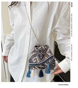 Detail of ethnic geometric woven bucket bag with colorful tassels and drawstring closure