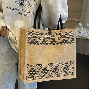 Large woven jute tote bag with ethnic geometric pattern and black shoulder straps