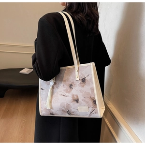 Détail d'un sac cabas à fleurs avec pompon blanc et fines anses en cuir synthétique