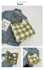 Close-up of green and white checkered woven tote bag with heart charm and green strap