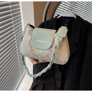 Detail of light green baguette bag with oriental floral jacquard fabric and metal chain
