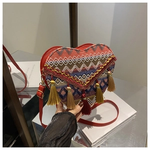 Detail of ethnic heart-shaped bag with colorful embroidery, red leather, and tassels