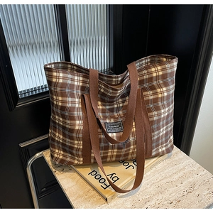 Détail d'un grand sac cabas à carreaux montrant la texture toile sur marbre