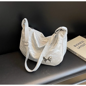 Détail du sac demi-lune argenté avec texture métallisée froissée et pendentif papillon