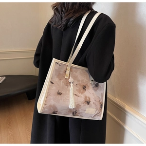 Détail du sac cabas à fleurs avec pompon en perles porté sur l'épaule par un mannequin