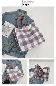 Detail of purple checkered canvas tote bag with heart charm and wide shoulder strap