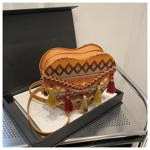 Detail of heart-shaped ethnic woven crossbody bag with colorful tassels in a luxury gift box