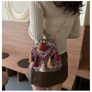 Detail of bohemian woven backpack featuring vibrant geometric patterns and silk tassels