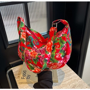 Detail of red floral hobo bag featuring traditional peony and phoenix patterns and silver buckle