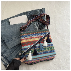 Détail d'un sac bohème tissé coloré avec pompons ethniques et large bandoulière brodée
