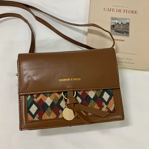 Detail of vintage brown leather crossbody bag with colorful geometric woven pattern