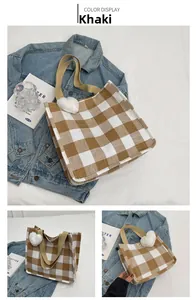 Detail of khaki checkerboard tote bag with brown straps and white plush heart charm