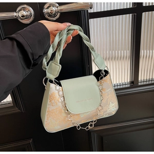 Detail of the green and beige baguette bag with architectural jacquard pattern and braided handle