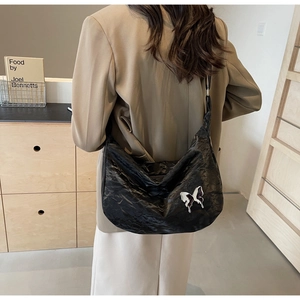 Détail du sac hobo plissé noir avec breloque papillon argentée et aspect texturé