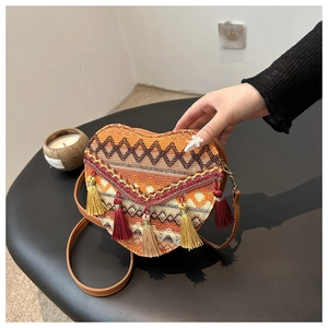 Detail of bohemian heart-shaped woven bag with geometric patterns and long tassels