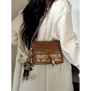 Brown retro crossbody bag with geometric pattern and cute rabbit charm on white coat