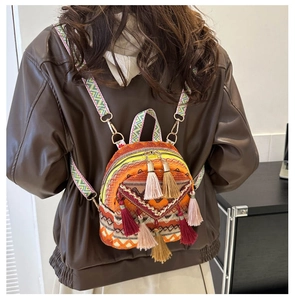 Detailed back view of mini ethnic backpack with orange bohemian patterns and tassels