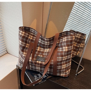 Détail d'un cabas à carreaux classique avec sangles marron et écusson de mode appliqué