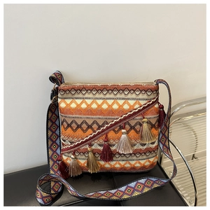 Détail d'un sac bohème tissé avec motifs géométriques et pompons décoratifs