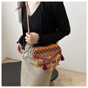 Detail of bohemian heart-shaped woven bag with ethnic patterns and colorful tassels