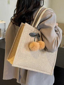 Minimalist beige linen tote bag for women with cherry plush charm shown on shoulder