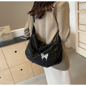 Détail du sac à bandoulière noir avec texture plissée et boucle papillon argentée chic