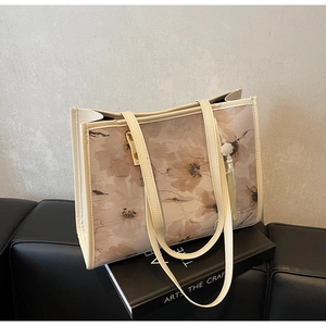 Détail du grand sac cabas à fleurs avec pompon en perles sur un canapé en cuir
