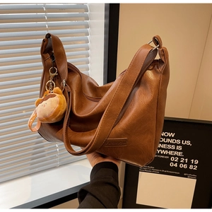 Detailed shot of warm brown lychee leather bag with teddy bear charm and fashion logo