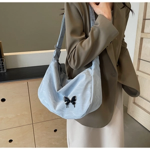 Détail du sac nuage bleu clair avec boucle papillon noire en métal et bandoulière