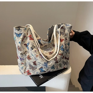Detail view of large canvas tote bag featuring colorful butterfly embroidery and webbing handles
