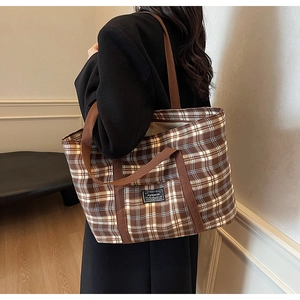 Détail d'un grand sac cabas à carreaux avec anses brunes et étiquette FASHION porté