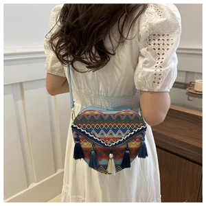 Detail of bohemian heart-shaped woven bag with colorful patterns and blue tassels