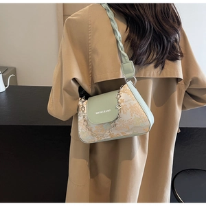 Detail view of a pale green and beige crossbody bag featuring floral embroidery textures