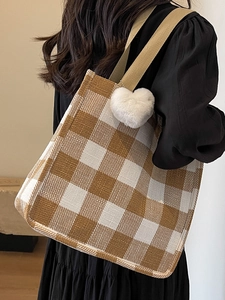 Brown and beige plaid tote bag with plush heart charm shown on a female model shoulder