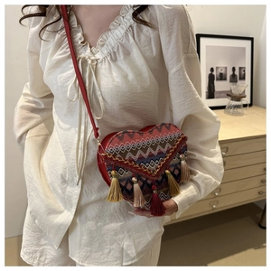 Detail of heart-shaped ethnic crossbody bag with embroidery and colorful tassels