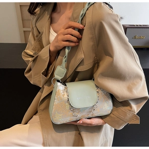 Detail of light green baguette bag with golden landscape print and metal chain strap