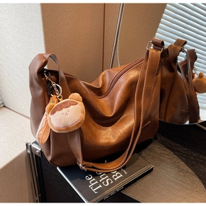 Detailed close-up of brown PU leather bag texture with cute bear charm and zipper