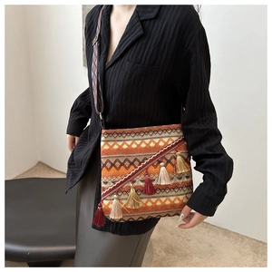 Détail d'un sac bandoulière bohème tissé avec motifs géométriques et pompons faits main