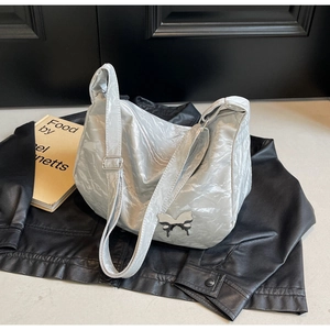 Détail du sac papillon argenté métallisé avec texture sur une veste en cuir