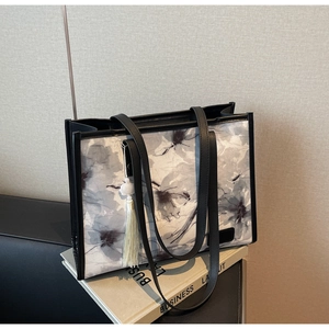 Détail d'un sac cabas floral avec imprimé fleurs gris-violet et accessoire de pompon noir
