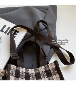 Detail of a brown plaid tote bag featuring adjustable woven shoulder straps and retro texture