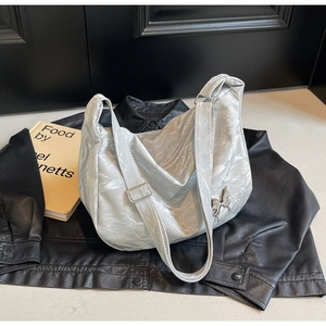Détail du sac à bandoulière argenté métallisé avec boucle papillon et texture plissée