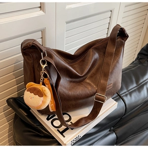 Detail of dark brown PU leather bag with silver buckle and cute plush charm accessory