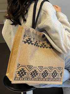 Large woven jute tote bag with black geometric tribal pattern and shoulder straps