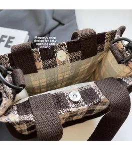 Detail of the magnetic buckle closure on a brown checkered fabric tote handbag