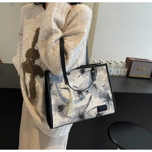 Gros plan d'un sac cabas au style français avec imprimé floral et détail de pompon blanc